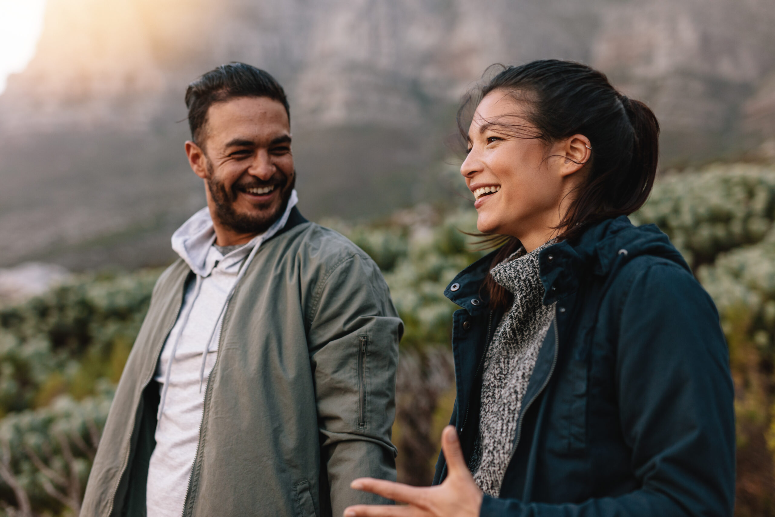 Portrait of happy young couple walking and talking in the countryside. Young man and woman enjoying on a nature hike.